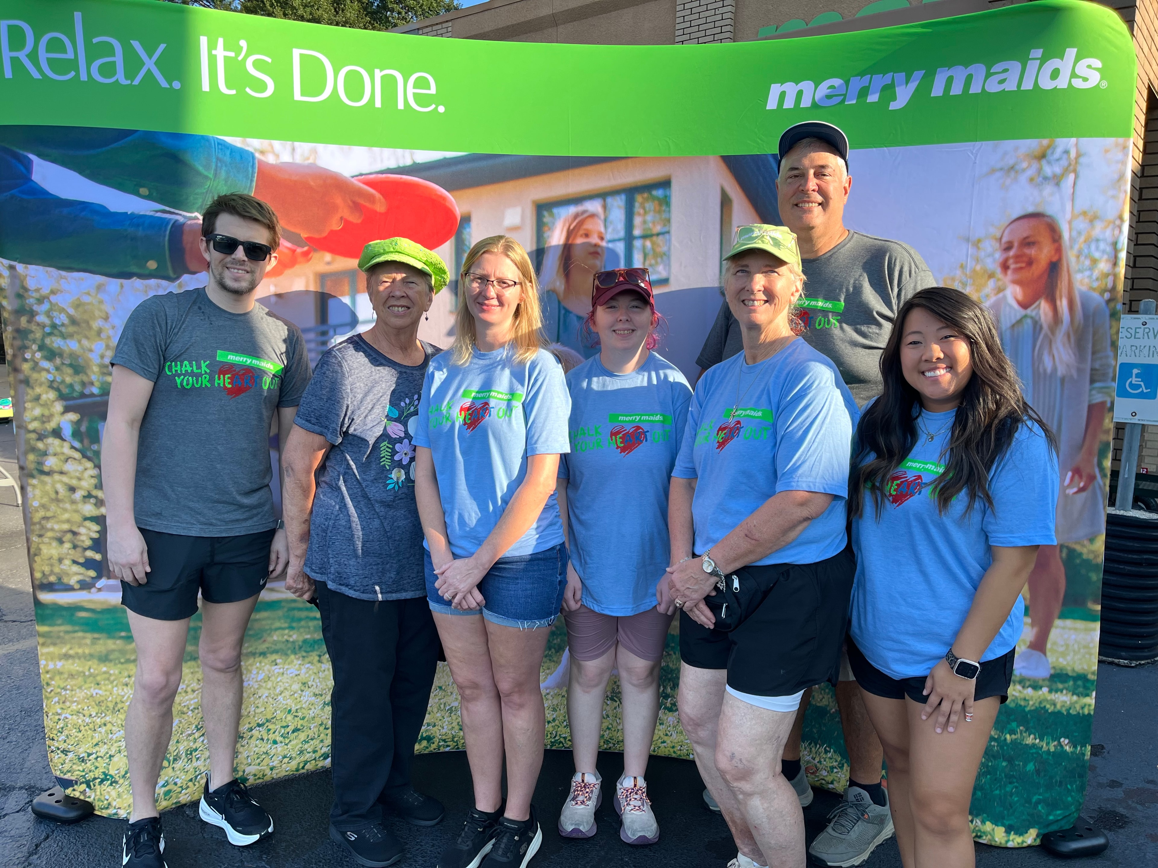Chalk Your HeART Out volunteer team in front of Merry Maids banner